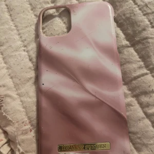 Rosa mobilskal från Ideal of Sweden - Snyggt rosa mobilskal från Ideal of Sweden med ett marmorerat mönster. Skalet har en elegant design och skyddar din telefon med stil. Perfekt för att ge din mobil en personlig touch!