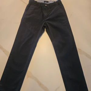 Mörkblå manchesterbyxor från Gant - Snygga mörkblå manchesterbyxor från Gant med klassisk design. Byxorna har en rak passform och knappar i midjan. Perfekta för en stilren look. Du får ett medel stort packet💙