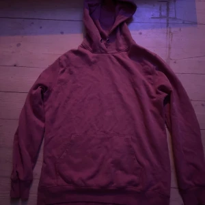 Röd hoodie från lager 157 - Säljer en röd hoodie från lager 157. Den har en klassisk design med en stor ficka framtill och en justerbar huva. Perfekt för en avslappnad stil.