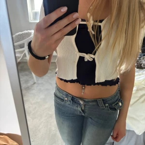 Vit ribbad sommartopp från Lindex - Säljer en söt vit ribbad bolerotopp från Lindex. Toppen har knytning framtill. Passar storlek xxs-s