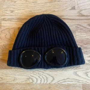 Cp company mössa - Tja, säljer denna feta Cp company mössa, 8/10 skick. Liten spricka i glaset på vänster sida (syns på bilden) Annars är den i mycket bra skick. Självklart äkta. Äldre model, därför de inte står ”Cp company” på glaset! Hör av er vid frågor. Fraktar spårbart via PostNord/InstaBox😄