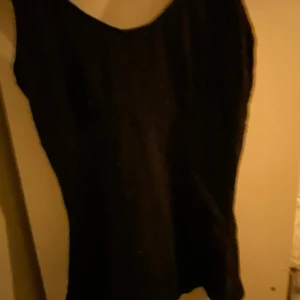 Svart linne  - Snygg svart linne med enkel design. Perfekt för en stilren look. Linne  har en klassisk passform och är ärmlös, vilket gör den idealisk för olika tillfällen.