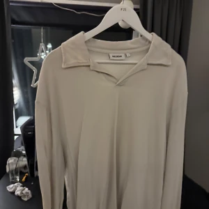 Beige långärmad tröja från Weekday - Säljer en stilren beige långärmad tröja från Weekday. Tröjan har en klassisk krage och är perfekt för en avslappnad look. Den är tillverkad i ett mjukt material som ger en skön känsla mot huden.
