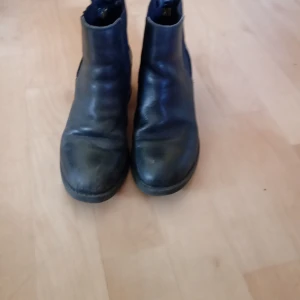 Svarta chelsea boots - Snygga svarta chelsea boots i skinn med rund tå och låg klack. Perfekta för en stilren look. Storlek dam 36.