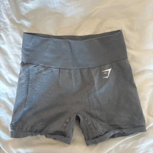 Grå shorts från Gymshark - Säljer ett par grå shorts från Gymshark med hög midja och seamless. Haft ett tag och är använda men är i väldigt gott skick! 