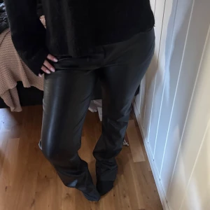 Svarta skinnbyxor - Snygga svarta skinnbyxor med en rak passform. Perfekta för en stilren look och kan enkelt matchas med olika toppar. Byxorna har en klassisk design och är ett måste i garderoben.