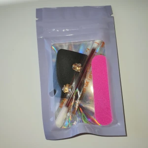 Skönhets kit - Säljer ett par glittriga örhängen i guld med stora, klara stenar. Setet inkluderar även en rosa nagelfil och en rengöringspinne för sår. Perfekt för att lägga till lite bling till din look!