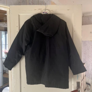 Svart jacka från Chevy - Säljer en svart jacka från Chevy med huva och dragkedja. Jackan har långa ärmar och praktiska fickor framtill. Perfekt för kyligare dagar.