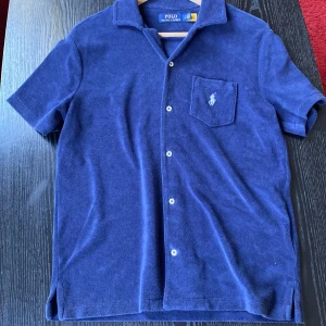 Blå frottéskjorta från Ralph Lauren - Säljer en blå kortärmad frottéskjorta från Ralph Lauren. Använd fåtal gånger, storlek S