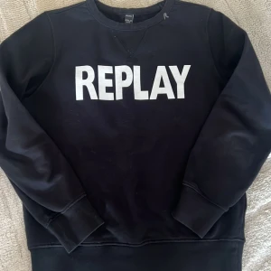 Svart sweatshirt från Replay - Säljer en svart sweatshirt från Replay med vit logga på bröstet. Tröjan har långa ärmar och en rund halsringning. Perfekt för en avslappnad stil.