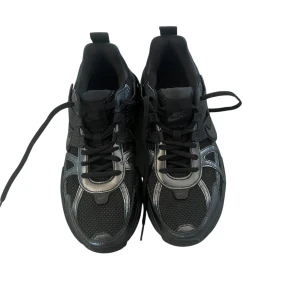 Svarta Nike sneakers - Snygga svarta Nike sneakers med en modern design och snörning. Perfekta för både träning och vardag. Skorna har en robust sula och diskreta detaljer som ger en stilren look. 