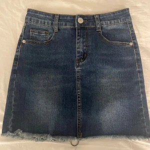 Jeanskjol med dragkedja - Spansk vintage jeanskjol i mörkblå denim med dragkedja baktill. Kjolen har aldrig används och har klassiska femficksdetaljer med en cool ringdetalj vid dragkedjan. 