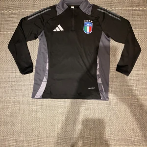 Svart och grå träningströja från Adidas - Säljer en svart och grå träningströja från Adidas med Italiens landslagsemblem på bröstet. Helt ny aldrig använd. Kan passa storlek S. Skick: 10/10