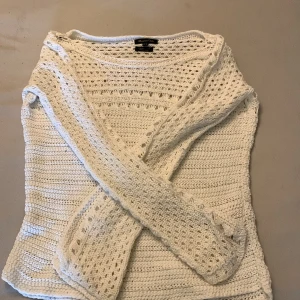 Vit stickad tröja från Massimo Dutti - Säljer en elegant vit stickad tröja från Massimo Dutti, tillverkad av italienskt garn. Tröjan har ett vackert hålmönster och långa ärmar, perfekt för en stilren look. Tillverkad i Spanien.