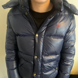 Blå pufferjacka från Ralph Lauren - Säljer en blå Ralph Lauren jacka. Det finns inget fel på jackan förutom ett gammalt hål som är igen sytt, fast inget man märker.skick 8/10 Jag köpte jackan på plick förra året för 2000kr. Nypris 5000. Jackan sitter perfekt om man är runt 160. Tveka inte på att fråga frågor, priset är inte hugget i sten så kom med förslag. 