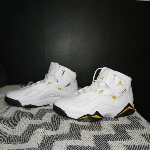 Vita och gula Nike Air Jordans Aldrig Använda!! - Snygga vita Nike Air Jordans med gula detaljer och svart sula. Skorna har en hög design med snörning och den ikoniska Jumpman-loggan. Perfekta för att ge din stil ett lyft! Endast provade
