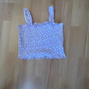 Ljuslila ribbad linnetopp - Söt ljuslila linnetopp med ribbad struktur och prickigt mönster. Toppen har breda axelband och en croppad passform, perfekt för varma dagar.