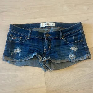 Blå jeansshorts från Hollister - Säljer ett par super snygga, väldigt lågmidjade vintage jeansshorts från hollister. De är i storlek 25 och är stretchiga, skulle säga att de passar någon som är ungefär mellan XS och S. Skriv för mått, fler bilder eller om ni undrar något!!💕🥰