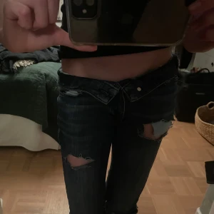 Mörkblå jeans med slitningar - säljer tyvärr mina absoluta favvo jeans då de blivit för korta i längden. Bootcut och lågamidjade/midwaist, vik ner för att få de mer low. Slitningar som ger en trendig look, passar någon som är under 165 skulle jag säga 👩🏽‍❤️‍👩🏽💓Bra skick!