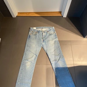 Levis 501 jeans i ljusblå denim - Säljer ett par klassiska Levis 501 jeans i ljusblå denim. De har en rak passform och är tillverkade i slitstarkt jeanstyg. Perfekta för en avslappnad stil. Storlek 30/30