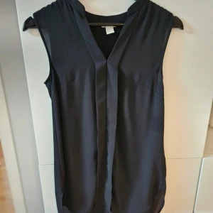 Svart ärmlös blus - Ärmlös chiffongblus från H&M. Använd en gång, därmed i mycket fint skick. 