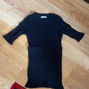 Svart ribbad topp från Pieces - Säljer en svart ribbad topp från Pieces. Toppen har en tight passform och trekvartsärmar, perfekt för en stilren look. Den är tillverkad i ett mjukt material som sitter bekvämt mot kroppen.