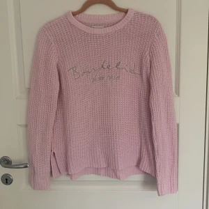 Rosa stickad tröja från Bondelid - Säljer en söt rosa stickad tröja från Bondelid med text på framsidan. Tröjan har långa ärmar och en rund halsringning. Perfekt för svala dagar och ger en mysig känsla. Passar bra till jeans eller kjol för en avslappnad look.