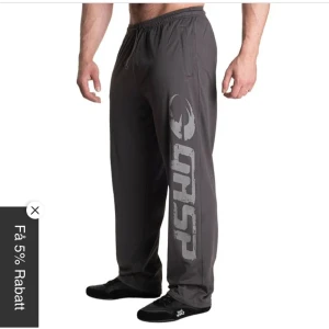 Grå träningsbyxor från GASP - Säljer ett par grå träningsbyxor från GASP med elastisk midja och stort tryck längs benet. Perfekta för gymmet eller avslappnade dagar. Byxorna har en loose passform för maximal komfort. Pris går att diskutera vid snabb affär!