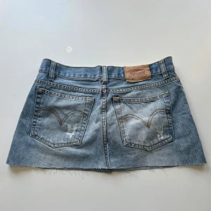 Levis kjol - Lågmidjad kjol, omsydd från ett par 501 Levis jeans. Midjemått: 80 cm, 40 cm mätt platt. Längd: 32 cm