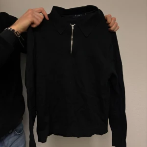 Svart långärmad tröja med dragkedja - Säljer en stilren svart långärmad tröja från Riley.. Tröjan har en dragkedja framtill och en klassisk krage.