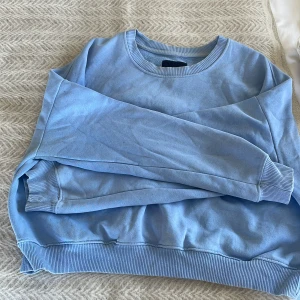 Ljusblå sweatshirt - Säljer en ljusblå sweatshirt med rund hals och långa ärmar. Perfekt för en avslappnad stil. Tröjan har ribbade muddar vid ärmslut och nederkant.