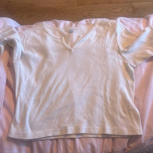 Vit långärmad tröja Brandy Melville - Vit långärmad tröja från Brandy Melville i 100% bomull. Tröjan har en avslappnad passform och en snygg v-ringning med liten detalj framtill. Perfekt basic att styla med jeans eller kjol för en clean look.