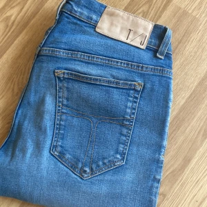  Tiger of Sweden w33 L 34 - Snygga blå skinny jeans från Tiger of Sweden med klassisk femficksdesign, gylf med dragkedja och knapp samt ljusbrun patch bak i midjan. Jeansen har smal passform och är tillverkade i mjukt bomullsjeansmaterial.