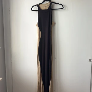 Svart och beige långklänning - Säljer en jättefin och kroppsnära långklänning i svart och beige som formar sig snyggt efter kroppen. Klänningen är i princip helt ny och har aldrig använts, men tyvärr är den för lång för mig som är 162 cm. Passar perfekt för dig som vill ha en elegant och tidlös look med en klänning som framhäver figuren.  Storlek ungefär S/M, stretchigt material för skön passform.  Hör gärna av dig vid frågor eller om du vill se fler bilder!