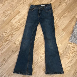 Blå bootcut jeans från Gina Tricot - Snygga blå jeans från Gina Tricot i klassisk bootcut-modell. Jeansen har fem fickor, normal passform och är tillverkade i ett mjukt denimtyg. Perfekta för dig som gillar en retroinspirerad look med utsvängda ben.
