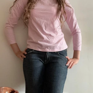 Ljusrosa långärmad topp med öppen rygg - Supersöt ljusrosa långärmad topp i bomull med snyggt korsad öppen rygg. Enkel framtill men med coola banddetaljer bak som gör den unik. Perfekt för dig som vill ha något basic men ändå med en twist.