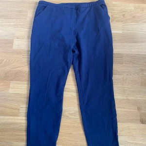 Mörkblå kostymbyxor med dragkedja - Snygga mörkblå kostymbyxor med klassisk passform och raka ben. Byxorna har fickor i sidorna och stängs med dragkedja och hake i midjan. Perfekta för en clean och stilren look. Kan mötas upp i Trollhättan eller Alingsås. Kan skickas men då tillkommer en fraktkostnad.