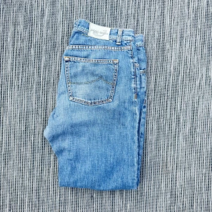  Jacob Cohen - Snygga ljusblå jeans från Jacob Cohen med klassisk femficksdesign och diskreta slitningar. Jeansen har raka ben och normal passform, perfekta för en avslappnad stil. Tillverkade i mjukt bomullstyg för extra komfort.!AI BESKRVINING! Om ni vill ha fler bilder eller om ni har andra funderingar och frågor skriv.
