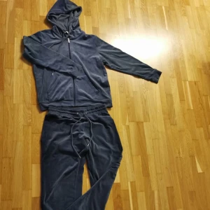 Mörkblå mjukis set från b.young - Mysig och söt mörkblå mjukis set från b.young som liknar Juicy Couture i mjuk och glansig velour. Byxorna har dragsko i midjan och en relaxed passform, perfekta för kalla dagar. Matchar med hoodie i samma material för en komplett look. Hör av er vid eventuella frågor💕💕