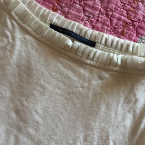 Krämvit blus från Valentino Jeans - Supersöt krämvit blus från Valentino Jeans med långa ärmar och snygg plisserad volangdetalj runt halsringningen. Mjuk och skön känsla, perfekt till jeans eller kjol. Enkel men ändå elegant stil som sticker ut.