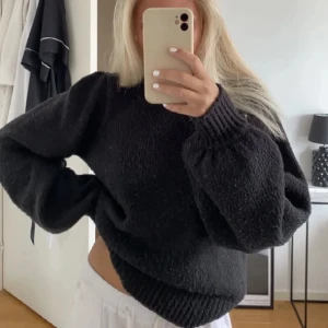 Svart oversized stickad tröja - Mysig svart stickad tröja med oversized passform och breda ärmar. Tröjan har ribbstickade muddar vid ärmslut och nederkant, perfekt för en avslappnad och trendig look.