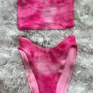 Rosa bandeau bikini från ASOS - Snygg rosa bandeau bikini från ASOS med high waist-trosa och tubtopp. Bikinin har en cool tie dye-effekt i olika rosa nyanser och är gjord i mjuk frotté. Perfekt för stranden eller poolen i sommar! Passar XS-M