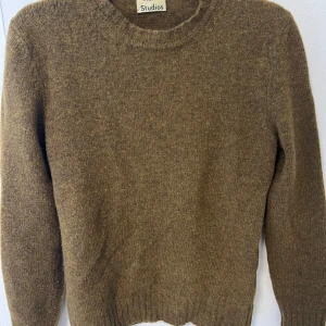 Brun stickad tröja från Acne Studios - Säljer en brun stickad tröja från Acne Studios i 100% lammull. Tröjan har rund halsringning, ribbade muddar och lång ärm. Endast använd fåtal gånger, i princip nyskick.