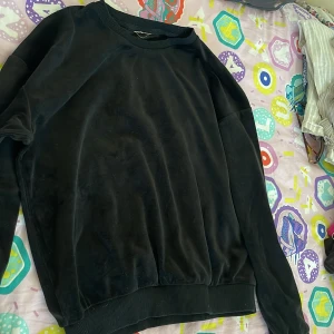 Svart sammetströja med rund hals - Mjuk svart tröja i sammet med rund halsringning och långa ärmar. Tröjan har ribbade muddar vid ärmslut och nederkant, perfekt för dig som gillar en stilren och chill look.