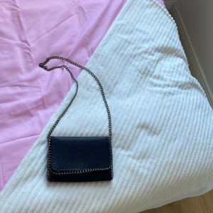 Svart axelväska med kedjerem -  Säljer en snygg svart väska. helt oanvänd.