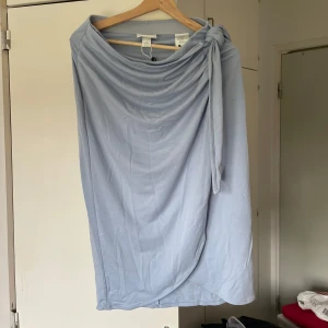 Ljusblå omlottkjol med knyt - Supersnygg ljusblå långkjol i mjuk material. Kjolen har omlottmodell med knyt i sidan som ger en chill och trendig vibe. Perfekt för dig som gillar en enkel men stilren look.