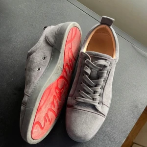 Christian Louboutin sneakers - Snygga grå sneakers från Louboutin med klassisk röd sula. Skorna har stilren design som passar till det mesta. Perfekta för dig som gillar exklusiva detaljer och vill sticka ut med en ikonisk sula. Kartong och påse medföljer