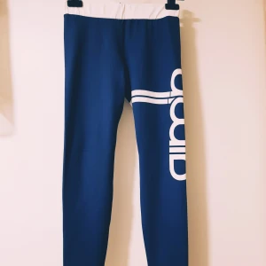 Blåvita leggings från aim'n, strl S - Snygga blå leggings från amn med vit midja och stort vitt tryck längs benet. Tillverkade i stretchigt material med 73% polyester och 27% spandex. Perfekta för träning eller chill, med bekväm passform och sportig look.  Helt & fint skick dock tvättludd mest på rumpan