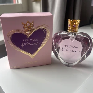 Vera Wang Princess parfym 50ml - Superfin Vera Wang Princess parfym i hjärtformad flaska med lila toner och en guldig krona som kork. Kommer i en söt rosa och lila ask med gulddetaljer. Doften är feminin och lekfull, perfekt för dig som gillar söta och fräscha parfymer.