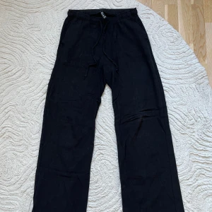 Svarta linnebyxor från Stradivarius - Säljer ett par svarta linnebyxor från Stradivarius med enkel passform, elastisk midja och raka ben. De har knytning runt midjan och är justerbara, materialet är luftigt och byxorna har två stycken fickor.  